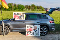 Türkheim, Deutschland – 08.05.2026: Demonstrierende protestieren mit Plakaten und deutschen Flaggen für politische Veränderungen und kritisieren Friedrich Merz.